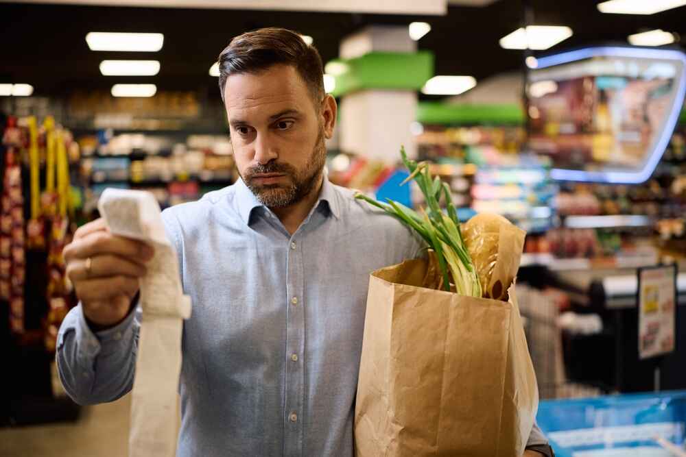 Worried man checking the bill after buying groceries in Abbotsfort